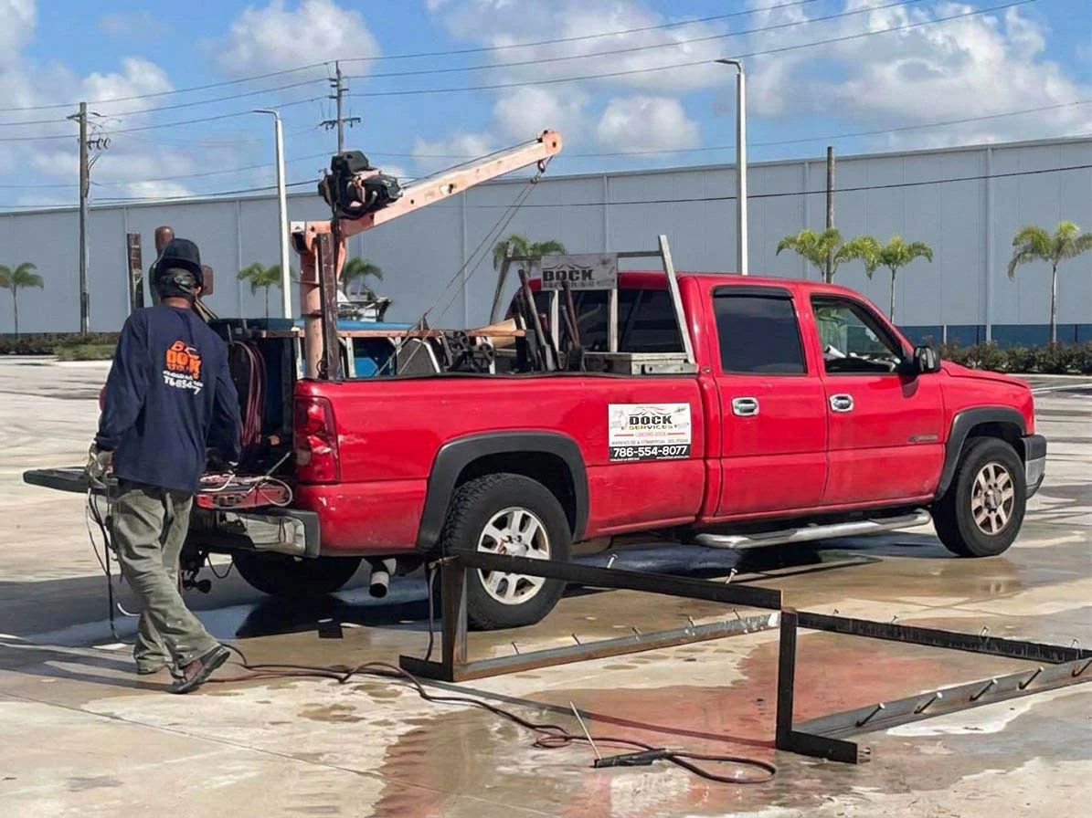 BXC Dock Services truck and technician welding a steel railing section in Miami