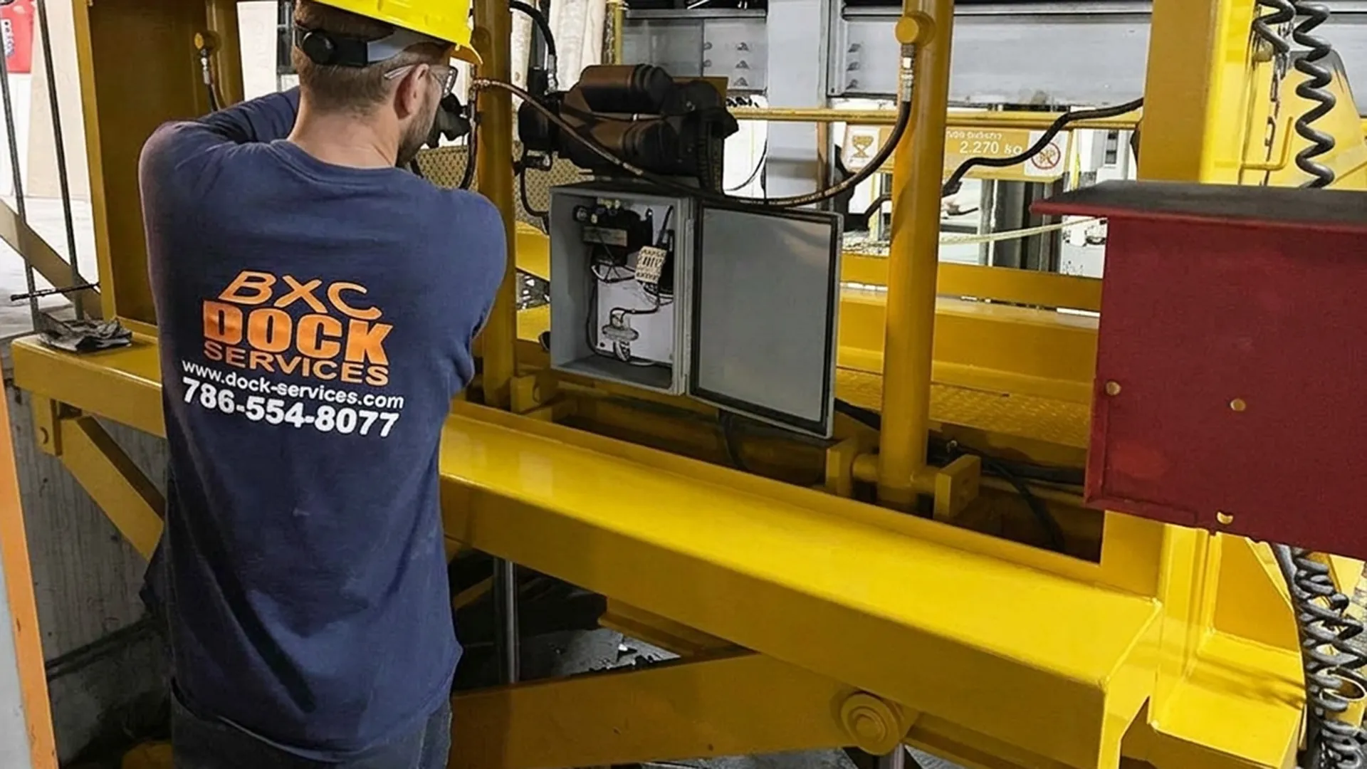 BXC Dock Services technician working on the open control box of a dock lift