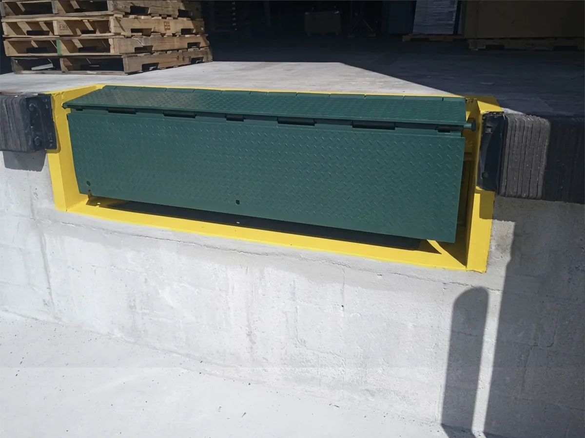 Recessed edge of dock leveler installed by BXC in a yellow steel frame set into the new concrete dock face