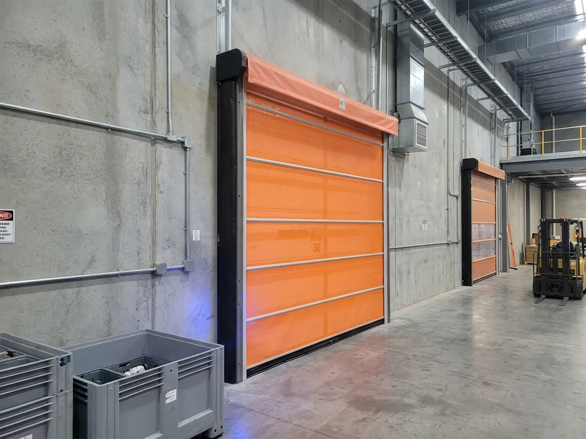 Orange roll-up screen doors on loading dock openings inside a warehouse
