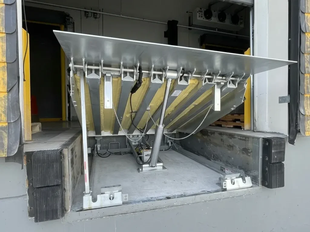 Hydraulic pit dock leveler with the deck raised at a loading dock door