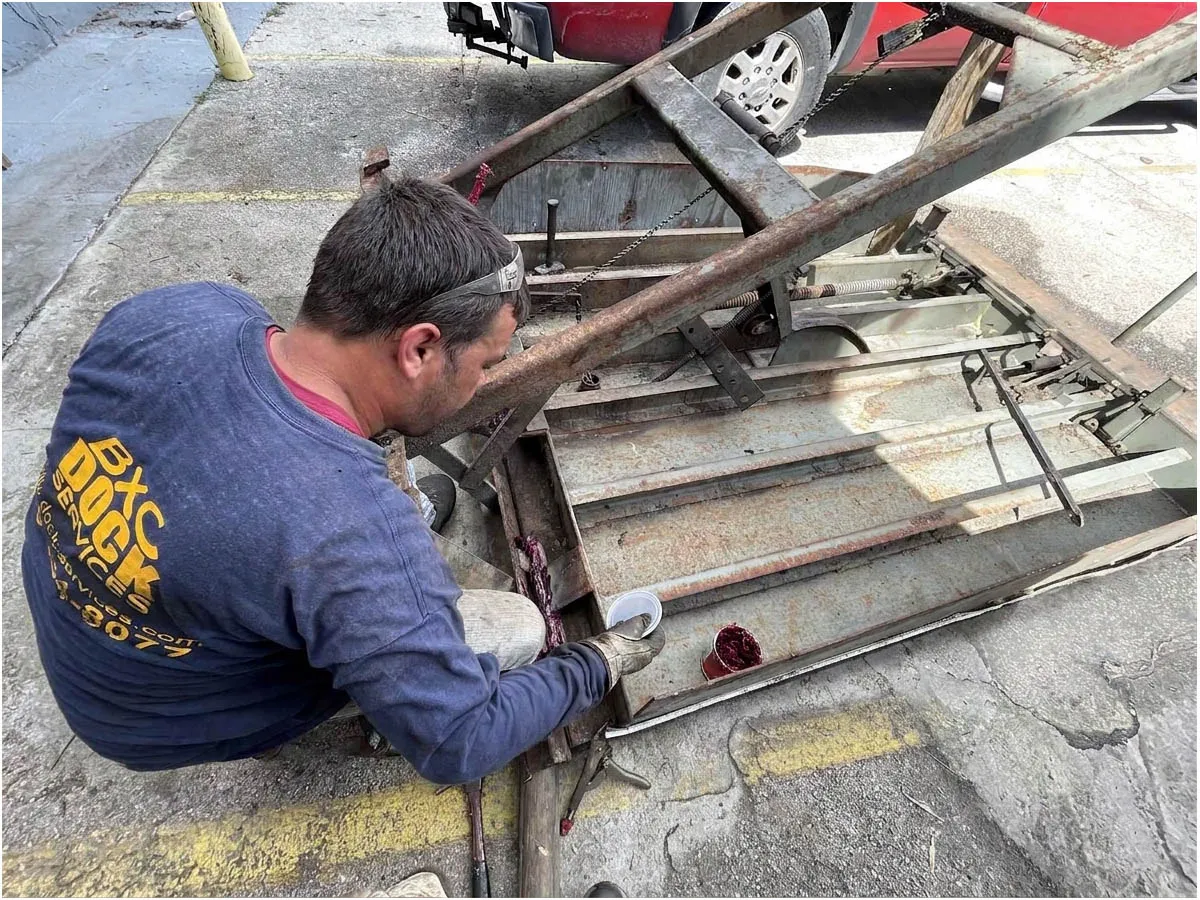 BXC technician repairing the hinge of a pit dock leveler